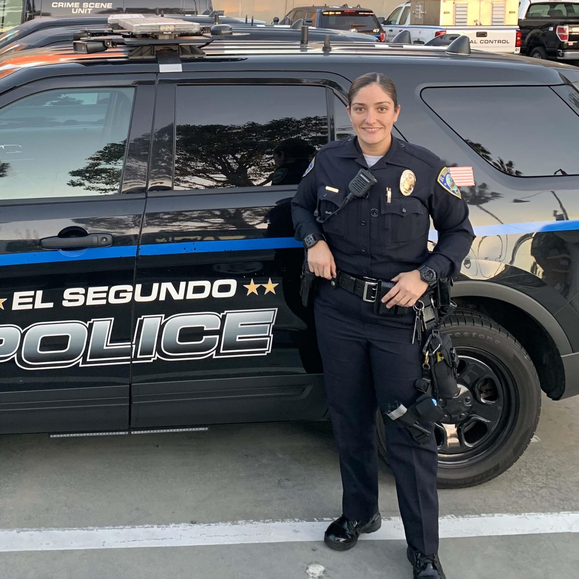 Female Police Officer smiling in front of a black police car