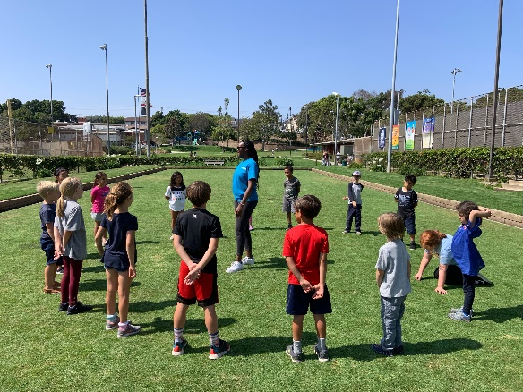 kids outside on a field with an adult for summer camp