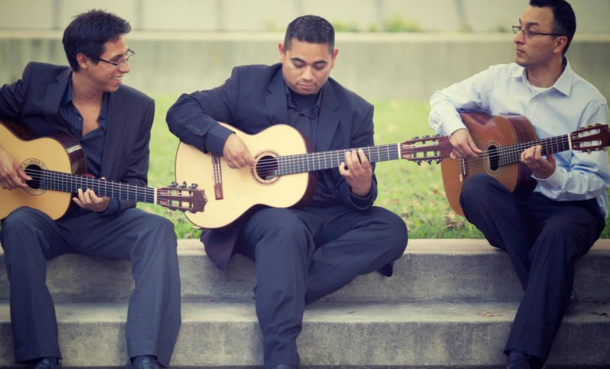 three men sitting playing guitar